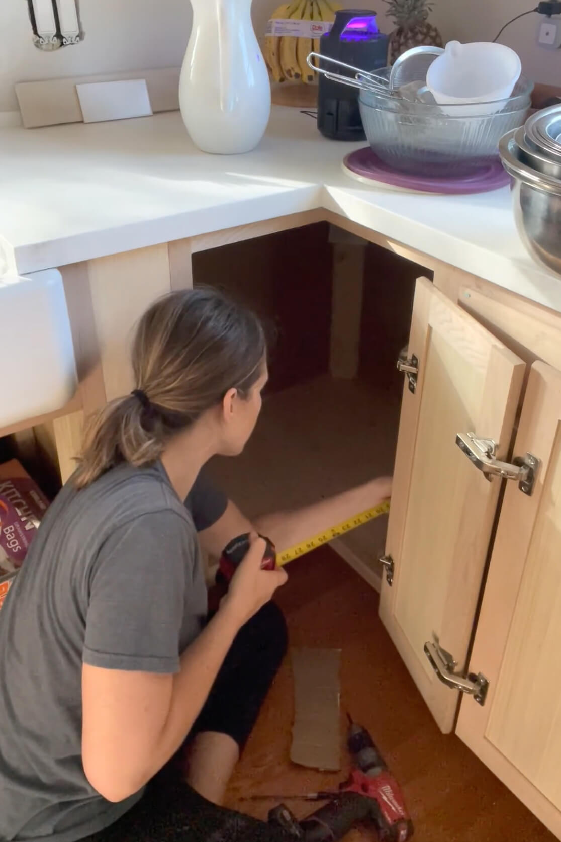 Measuring while adding shelves to a kitchen cabinet.